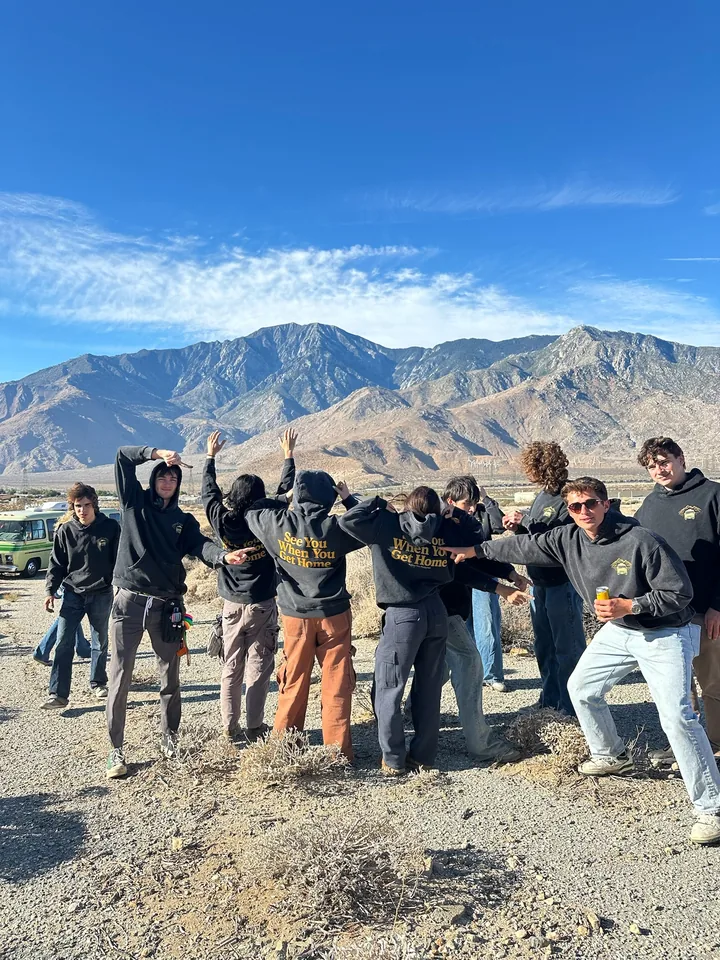 Crew members playfully posing together beneath the desert mountains
